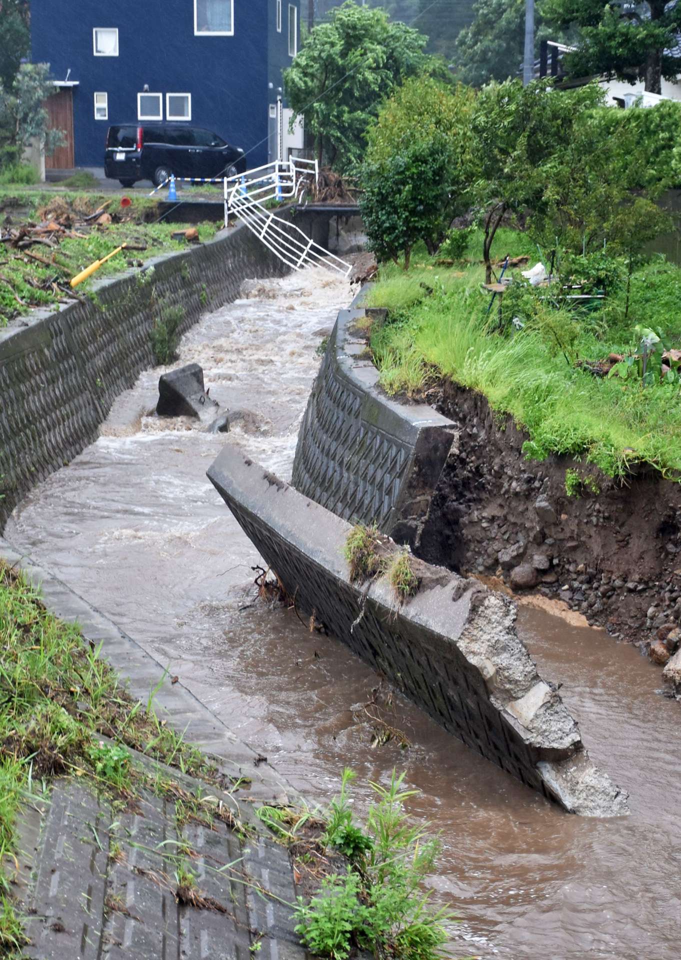 〈再びの激しい雨で倒壊寸前〉８日の大雨で崩れた護岸が倒れそうな枦山川＝２１日午後４時半、姶良市平松