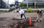 和田川の氾濫で出た土砂をスコップで集める住民＝鹿児島市和田３丁目
