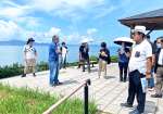 八代海（不知火海）を望みなから水俣病の歴史について説明を受ける参加者ら＝２３日、熊本県水俣市の大崎鼻公園