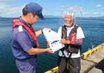 釣り客にライフジャケット着用を呼びかける海上保安官＝７月、霧島市福山の福山港湾緑地広場