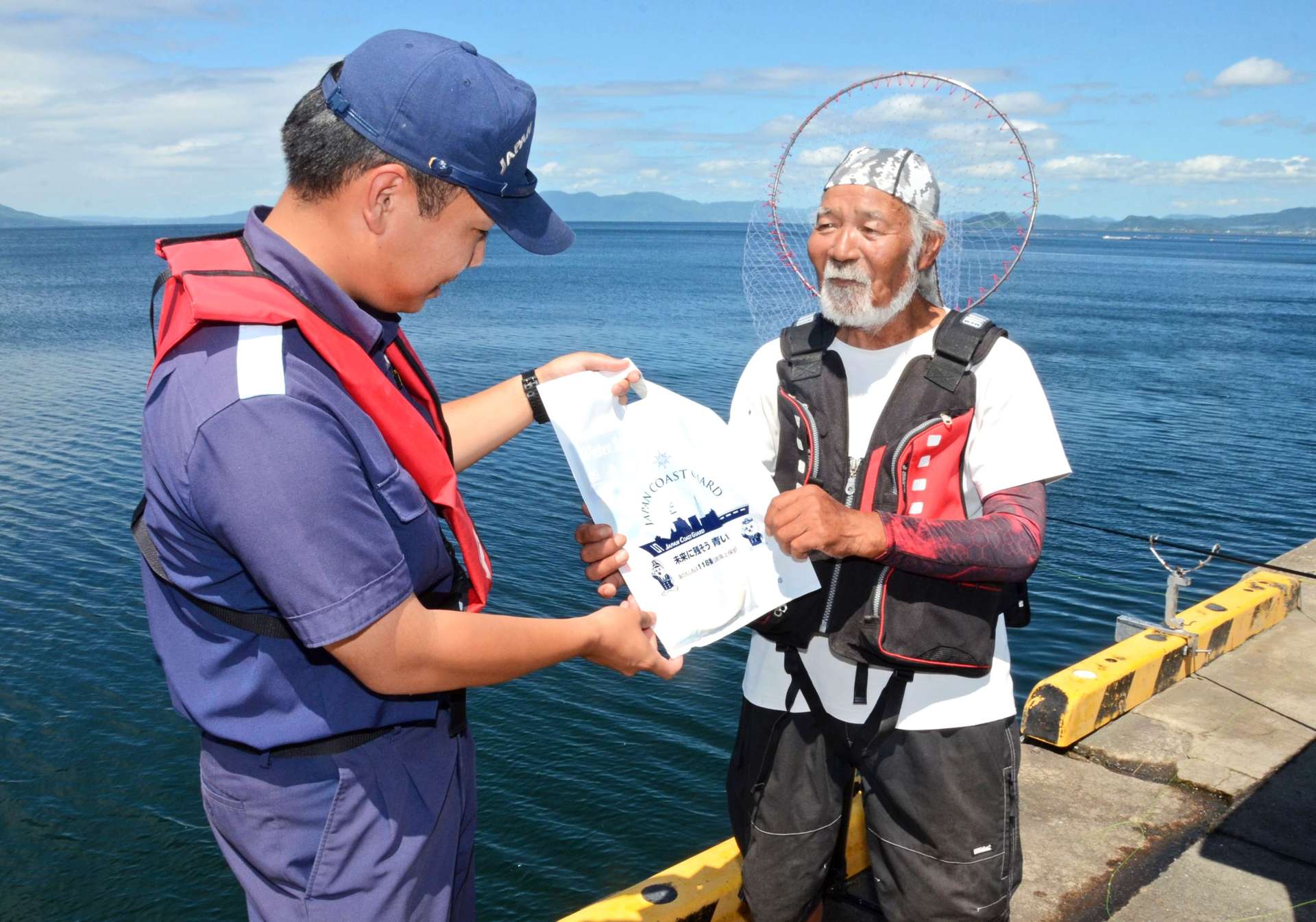 釣り客にライフジャケット着用を呼びかける海上保安官＝７月、霧島市福山の福山港湾緑地広場
