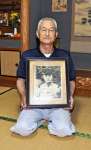 兄榮次さんの写真を手にする内田正道さん＝霧島市隼人町神宮の自宅