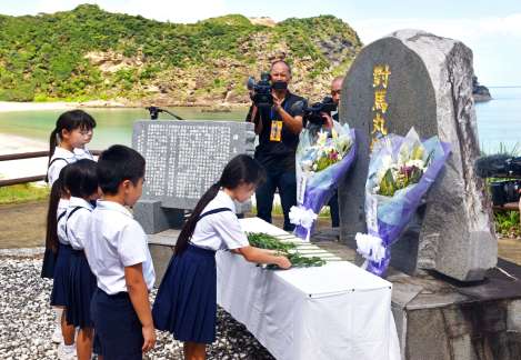 多くの遺体が流れ着いた船越海岸の慰霊碑に献花する小学生＝２４日、宇検村