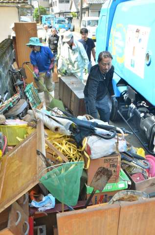 〈関連〉水没した家財道具を屋外に運び出すボランティアや市職員ら＝２４日午前、鹿児島市和田３丁目