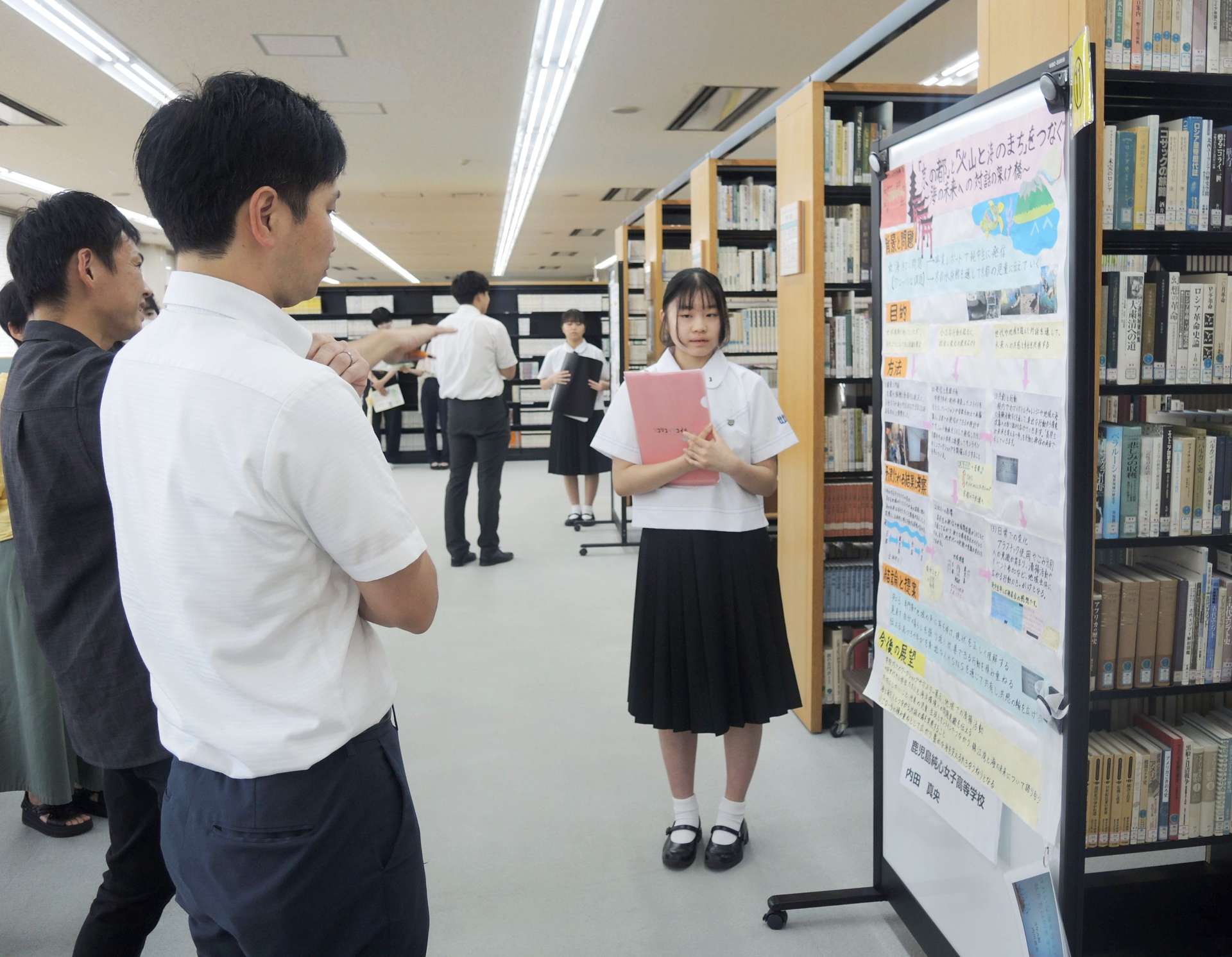 工夫を凝らしたポスターを使い研究成果を説明する生徒＝鹿児島市の鹿児島国際大