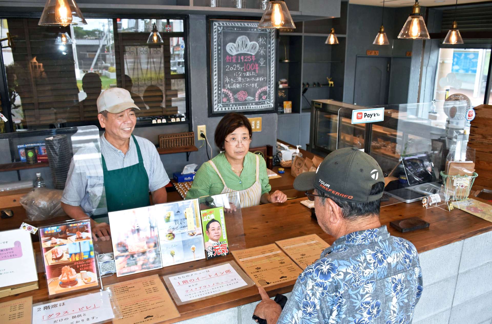 閉店を知って訪れた客と話す森田康之さん（左）と恵子さん＝２３日、姶良市加治木