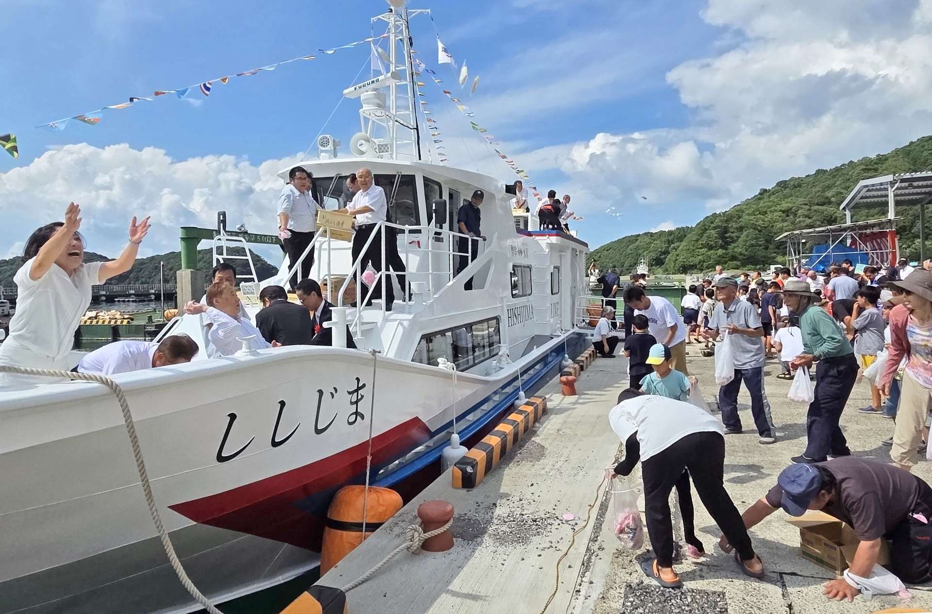 真新しい船からの餅まきを楽しむ住民ら＝２３日、長島町獅子島の幣串港