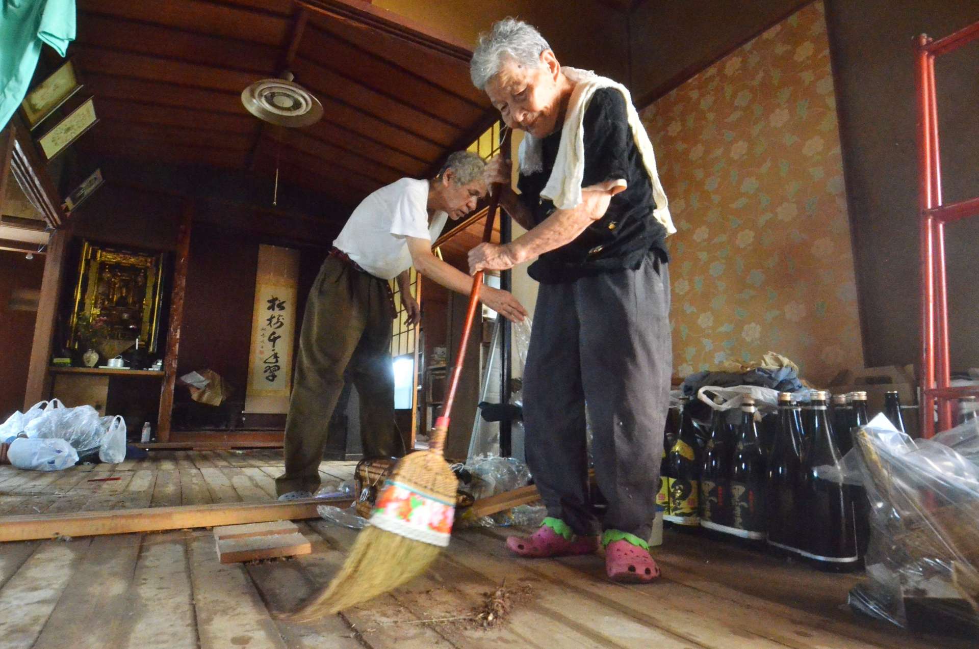 床上まで浸水した自宅を掃除する藤元ミエ子さん（右）＝２４日午前、鹿児島市和田３丁目