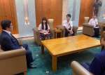 塩田康一県知事にシンガポールでの交流活動を報告する大学生と高校生＝鹿児島県庁