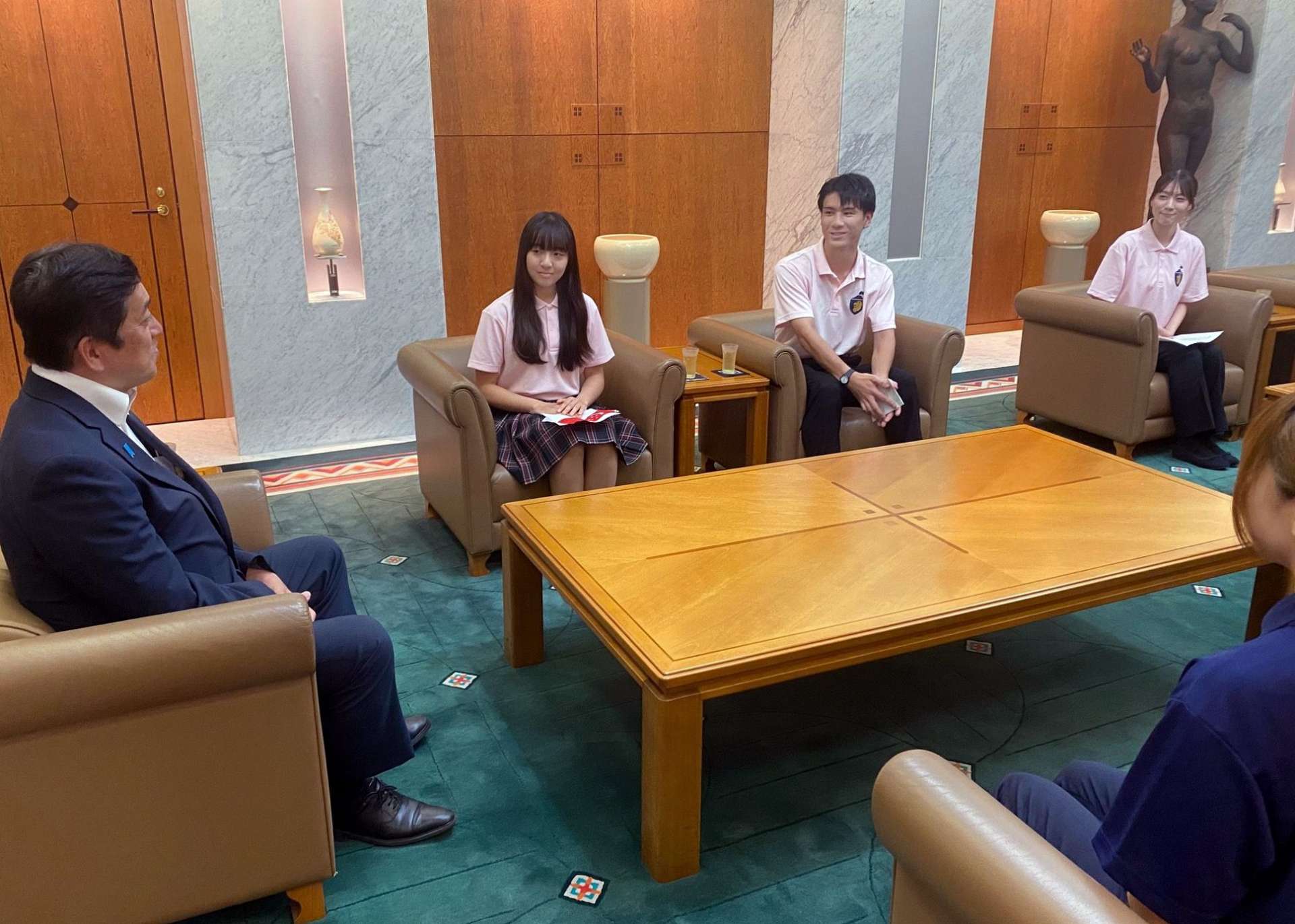 塩田康一県知事にシンガポールでの交流活動を報告する大学生と高校生＝鹿児島県庁