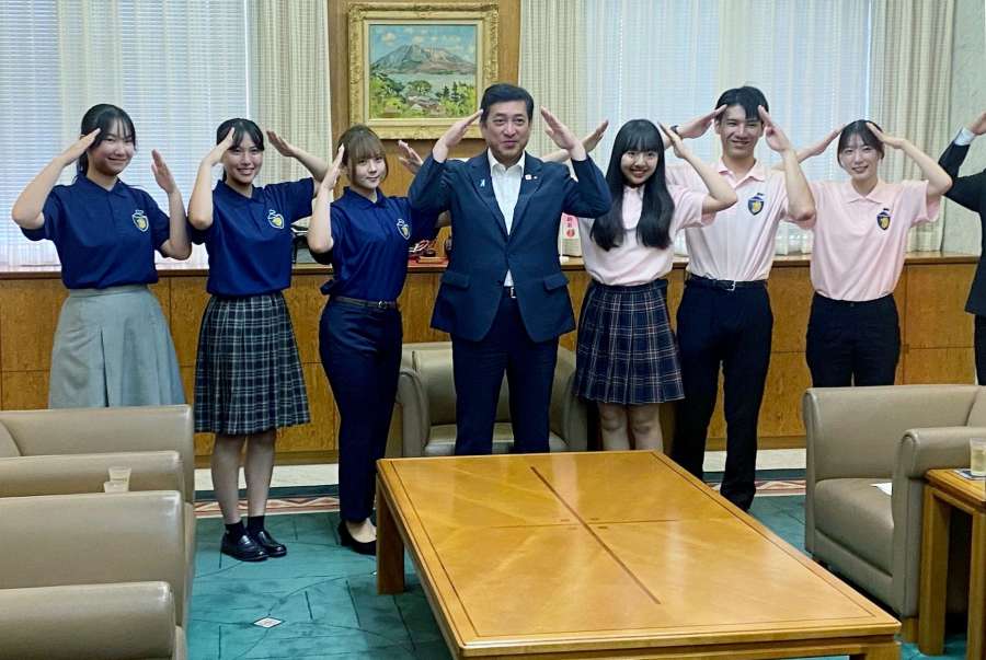 桜島ポーズを取るシンガポールへの派遣団員と塩田康一県知事（中央）＝鹿児島県庁