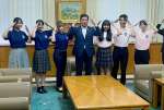 桜島ポーズを取るシンガポールへの派遣団員と塩田康一県知事（中央）＝鹿児島県庁