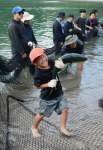 勢いよくはねるブリと格闘する子どもたち＝長島町のあずま海水浴場