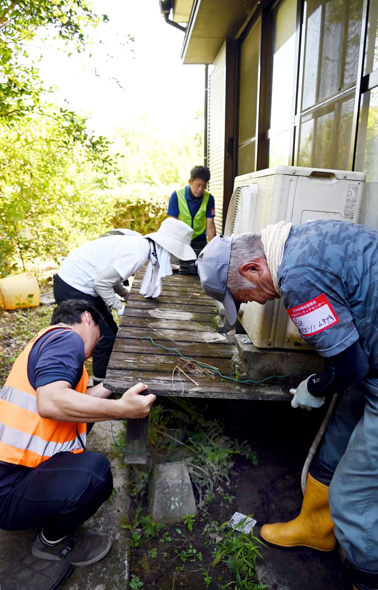 冠水して傾いたテラスを持ち上げるボランティア＝２８日、南さつま市加世田内山田