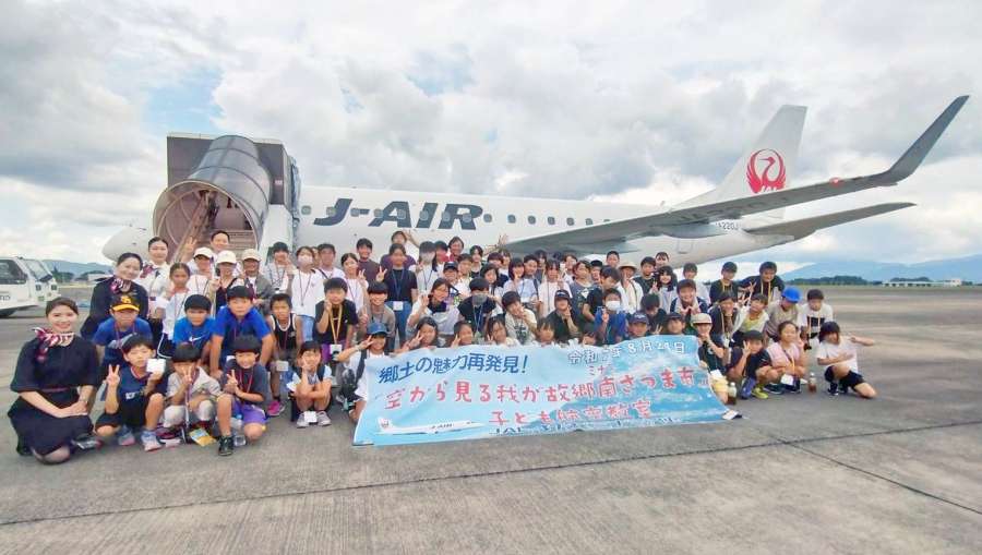 ジェイエア機で遊覧フライトに臨む小中学生＝霧島市の鹿児島空港（南さつま市提供）