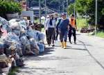 災害ごみが積まれた道路を歩き、活動場所へ向かうボランティア＝２８日、南さつま市加世田内山田