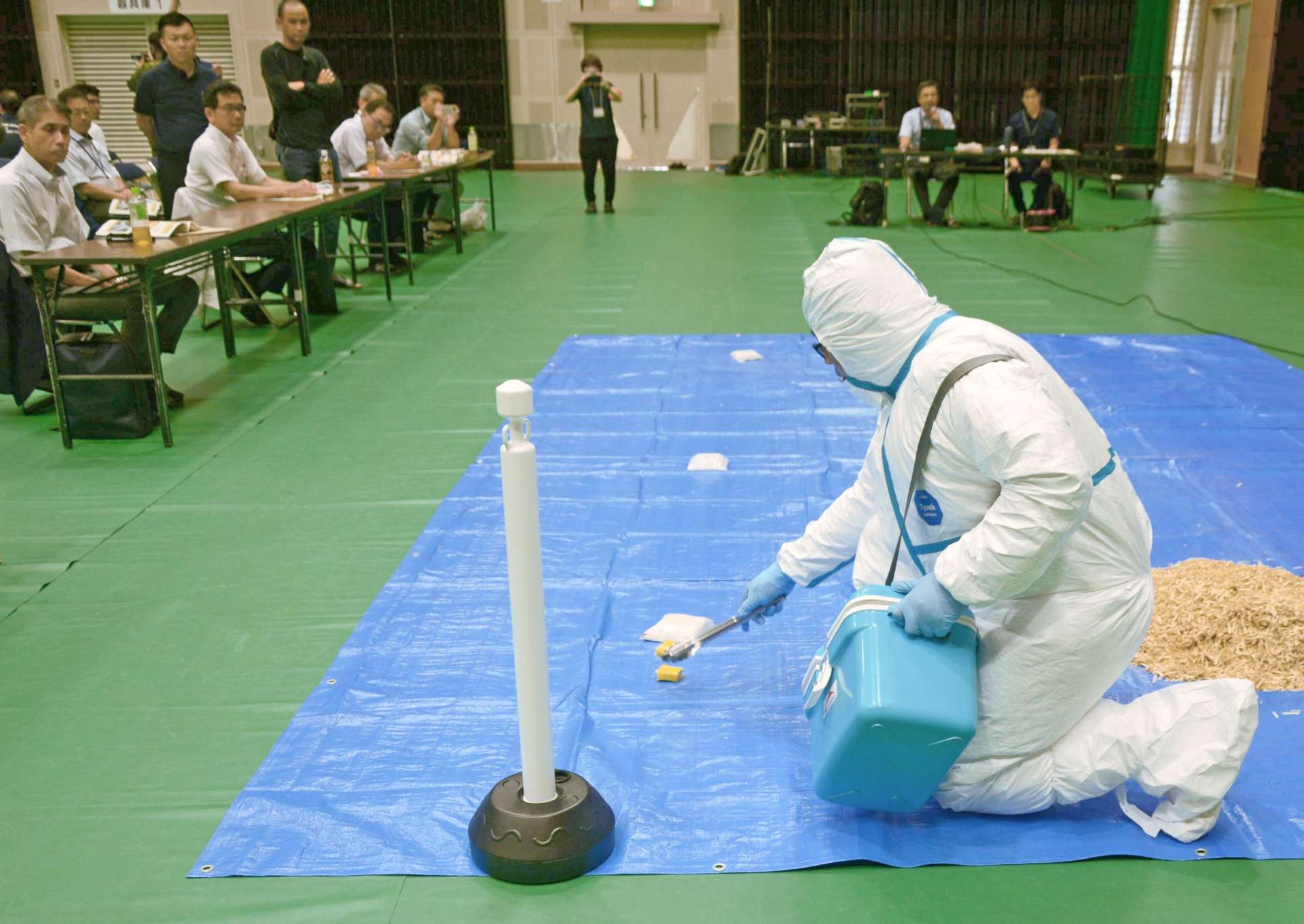 豚熱経口ワクチンの散布作業を実演する関係者＝２９日、さつま町船木の宮之城総合体育館