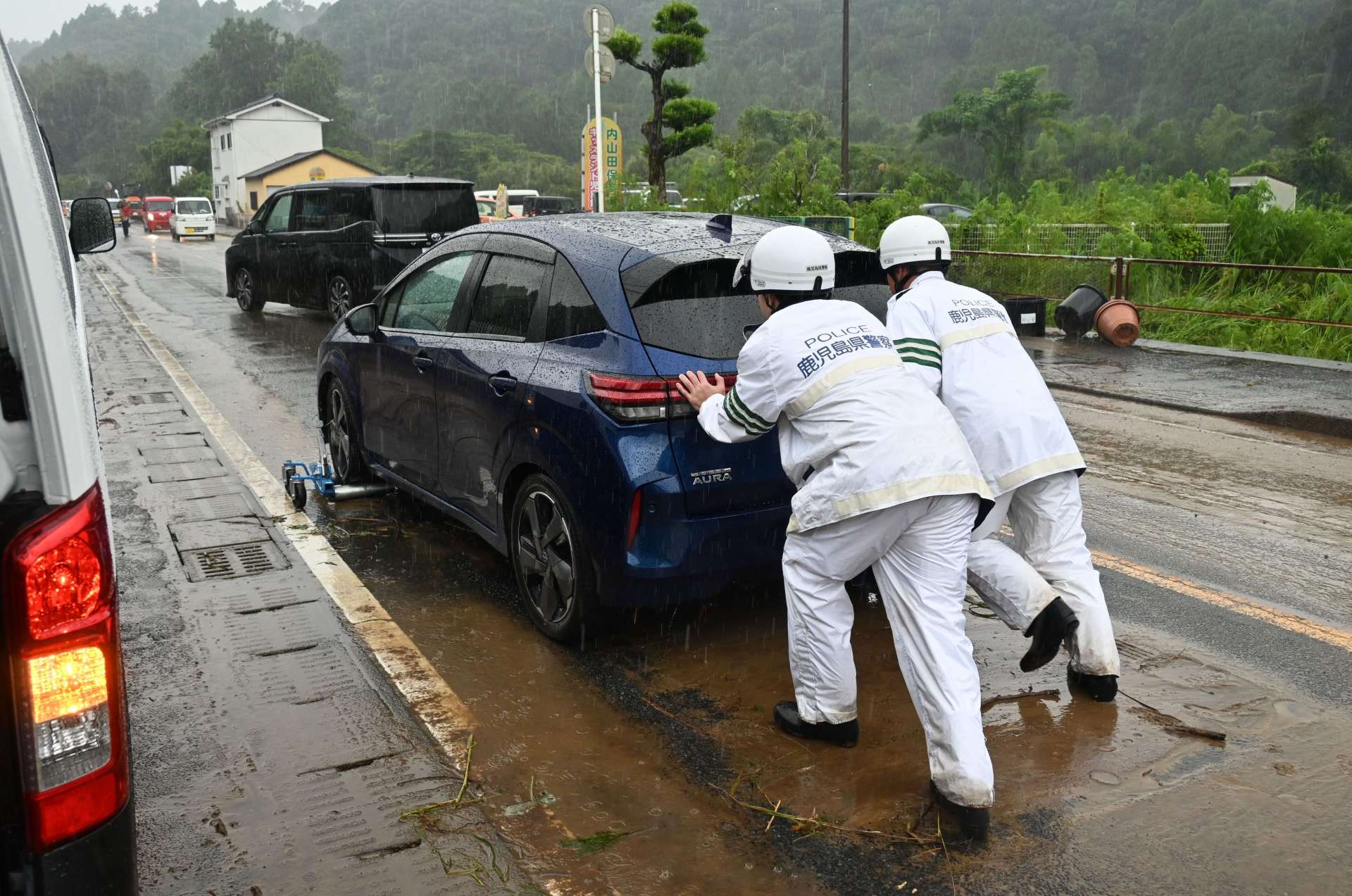 水没した車を移動させる警察官＝２２日、南さつま市加世田内山田
