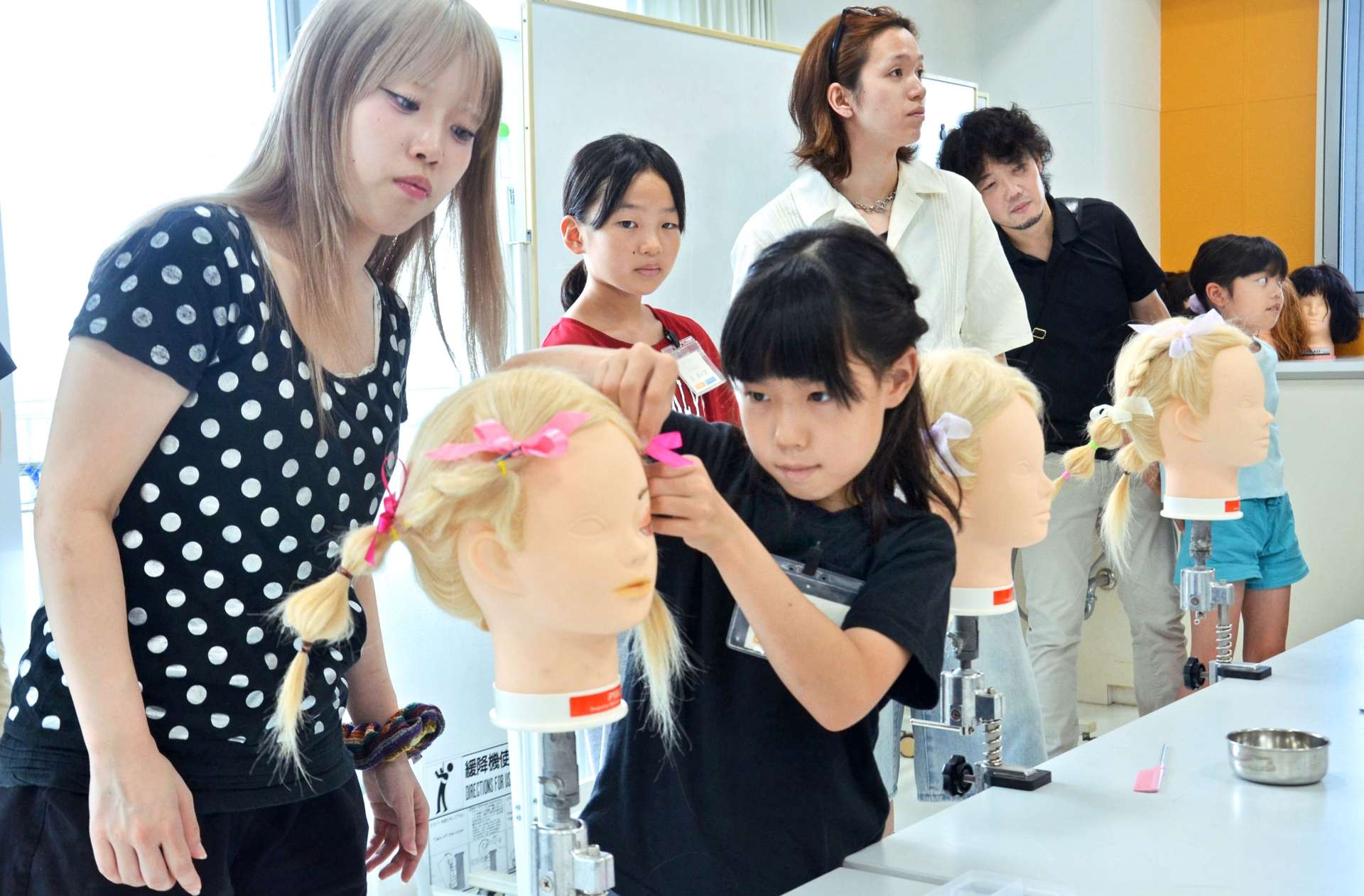 真剣な表情でヘアアレンジに挑戦する参加者＝８月２３日、鹿児島市上荒田町の赤塚学園