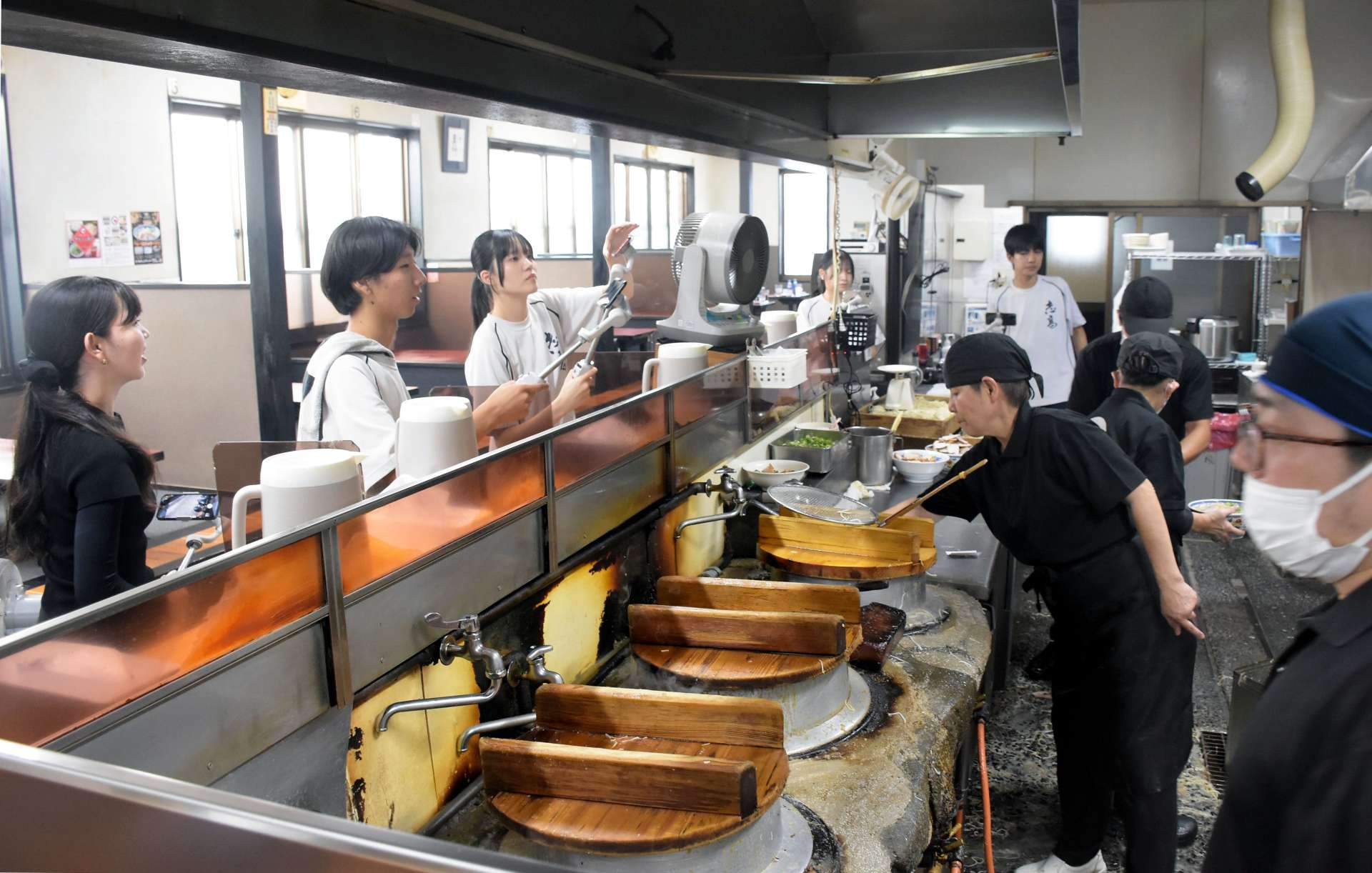 人気ラーメン店の厨房を撮影する志布志高校の生徒＝志布志市志布志町志布志２丁目