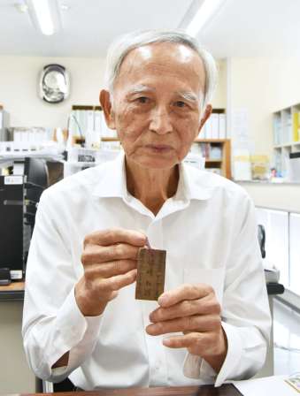戦時中、服にくくりつけていた名札を手にする県遺族連合会の浜崎和則副会長＝鹿児島市