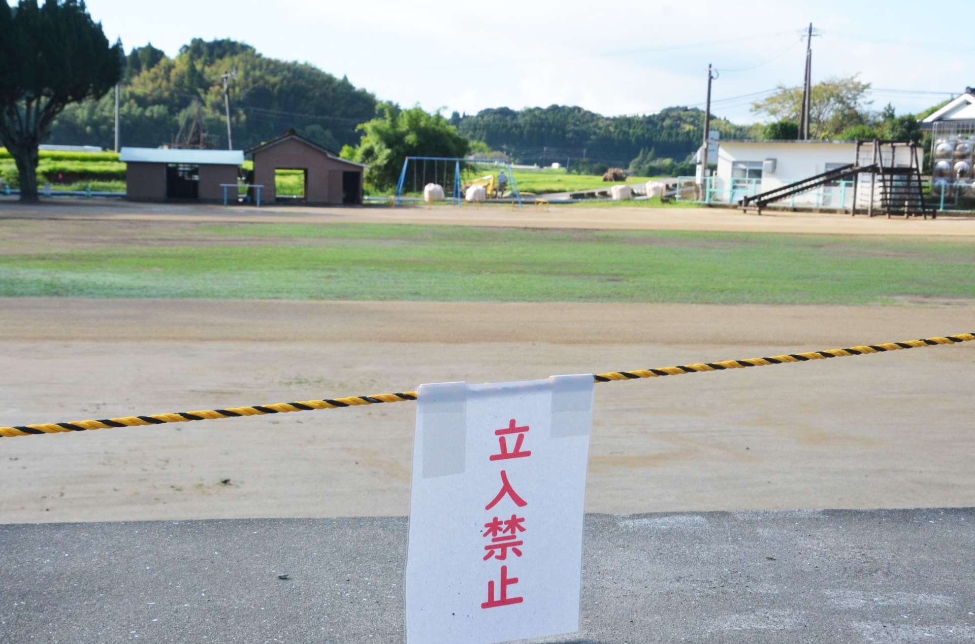 新学期に間に合わせるため急ピッチで復旧作業を終えた校庭。近くを流れる網掛川では護岸工事が続く＝１日、姶良市の竜門小学校