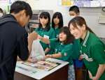 商品を渡し、接客する子どもたち＝日置市伊集院のセブン－イレブン伊集院徳重店
