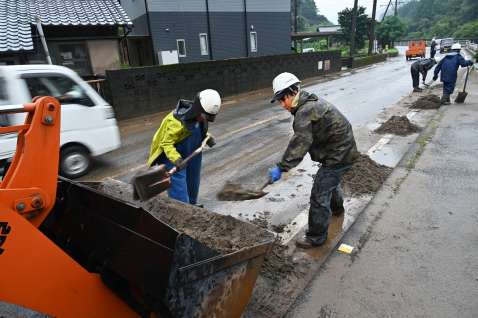 国道に流入した土砂を撤去する作業員＝２２日午前９時すぎ、南さつま市加世田内山田