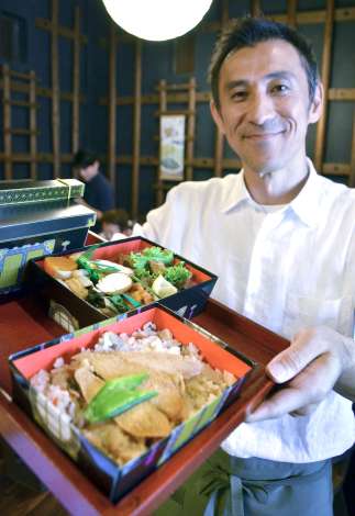 郷土料理が詰まった「島津弁当」を持つ日向時間の坂元寛之代表＝都城市早鈴町