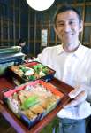 郷土料理が詰まった「島津弁当」を持つ日向時間の坂元寛之代表＝都城市早鈴町