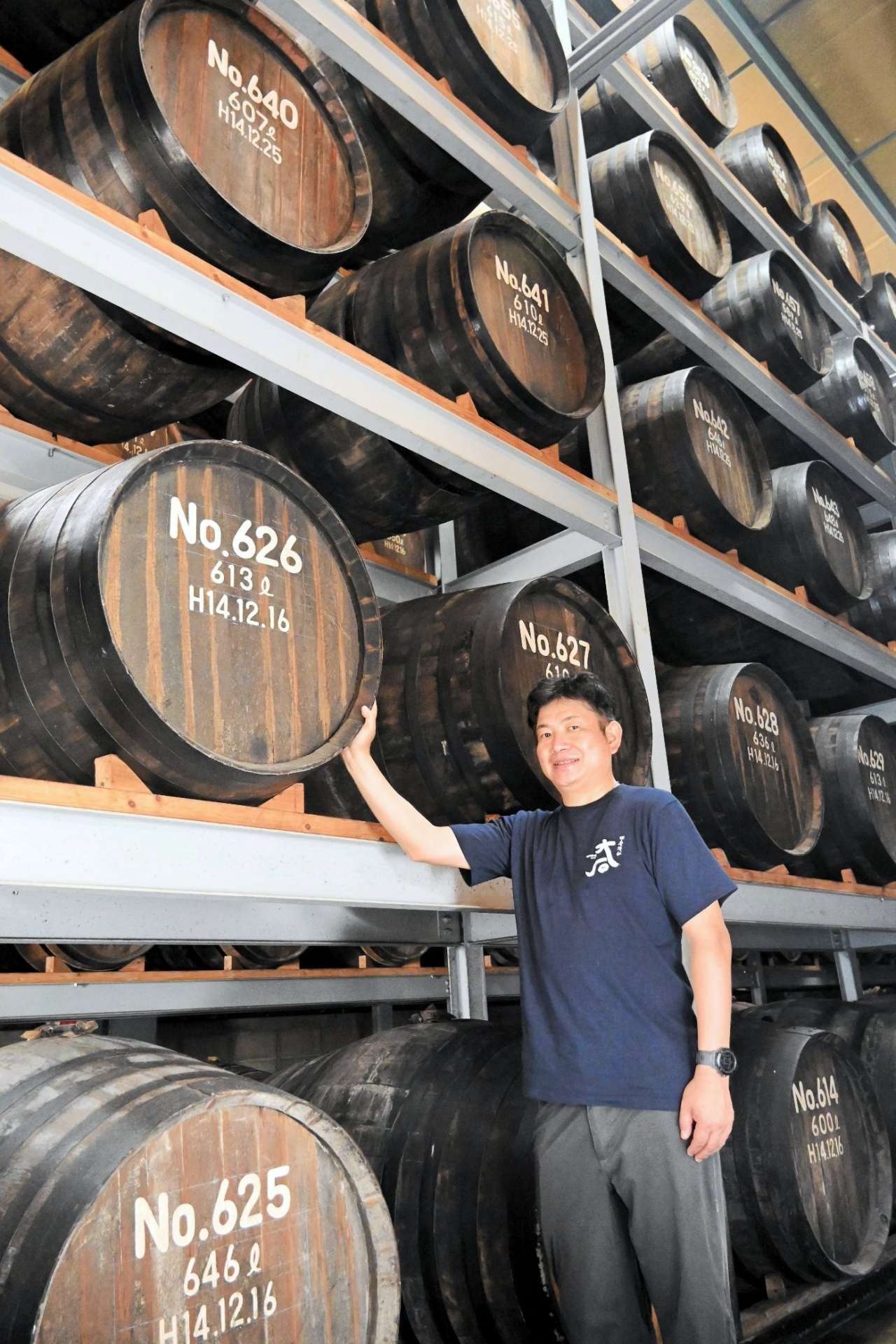 天井近くまでずらりと樽が並んだ倉庫を案内する大石酒造場の大石和教専務＝熊本県水上村