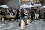 激しい雨の中、傘をさして足早に歩く市民＝１０日午前９時２３分、鹿児島市東千石町