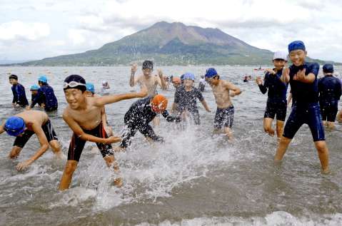 桜島を眼前に望む磯海水浴場で、初泳ぎを楽しむ小学生＝７月１０日、鹿児島市の磯海水浴場