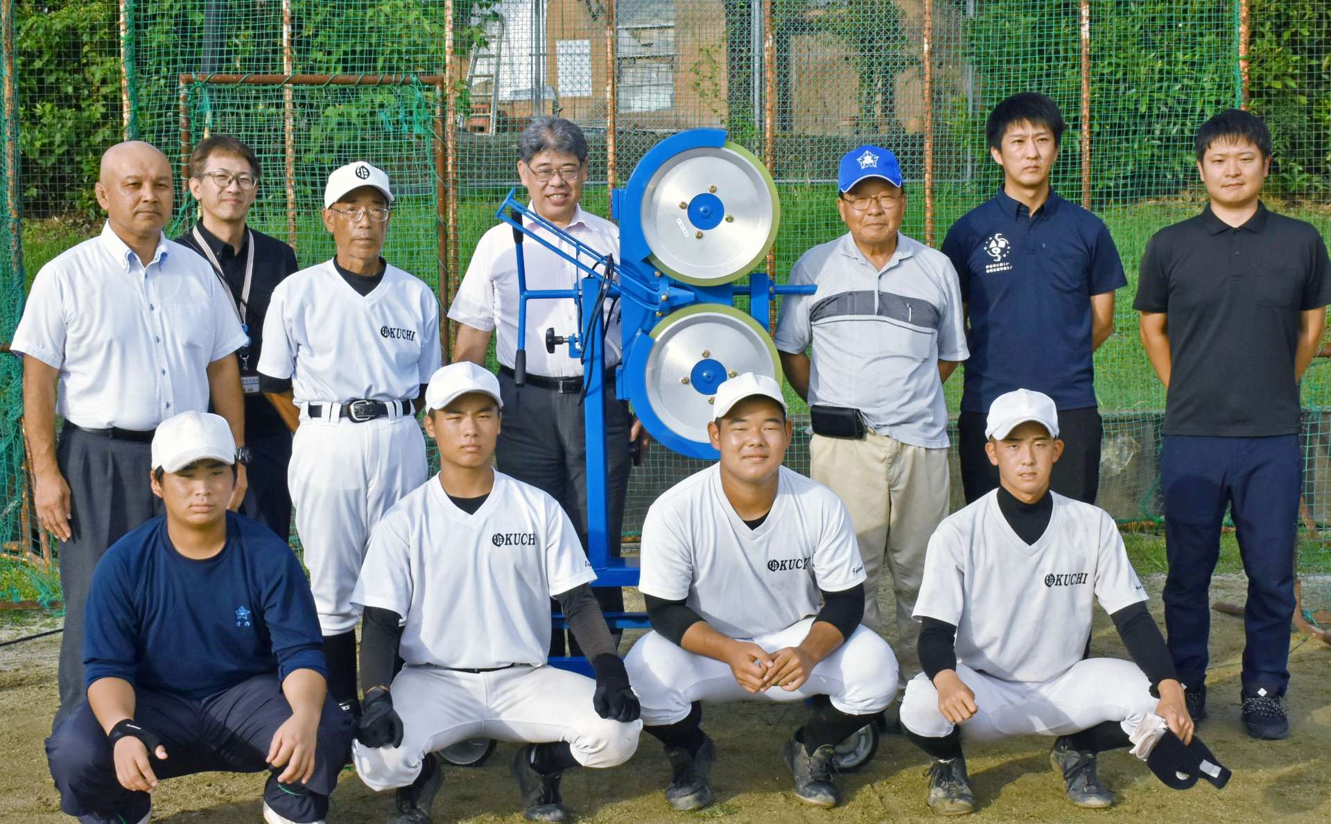 　母校野球部にピッチングマシンを贈った同窓会メンバーら＝１７日、伊佐市の大口高校　