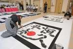 力強い筆運びで揮毫する書家＝２１日、鹿児島市の県護国神社