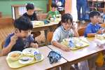 給食でイワシの丸干しを頬張る子どもたち＝阿久根市の山下小学校