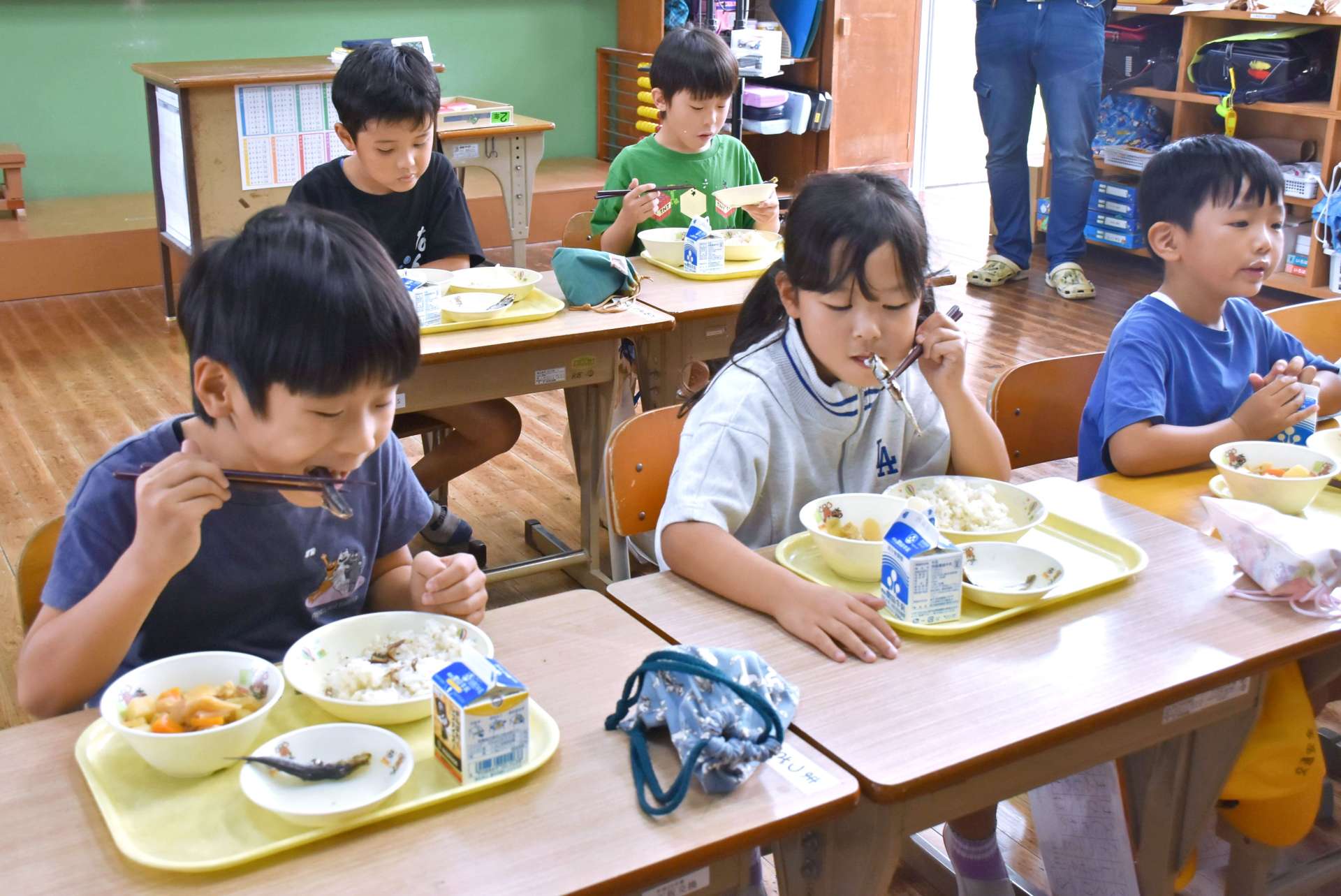 給食でイワシの丸干しを頬張る子どもたち＝阿久根市の山下小学校