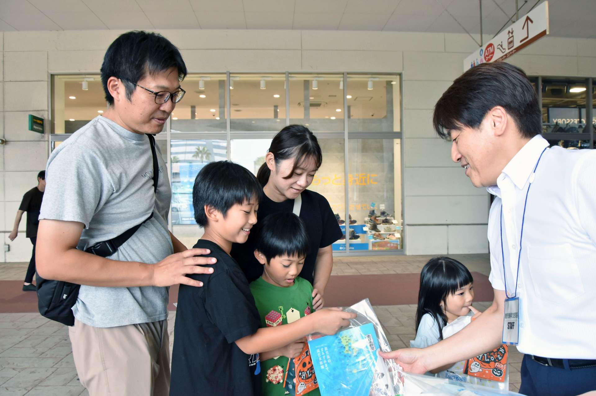 試読紙を受け取る家族＝１８日、鹿児島市与次郎１丁目