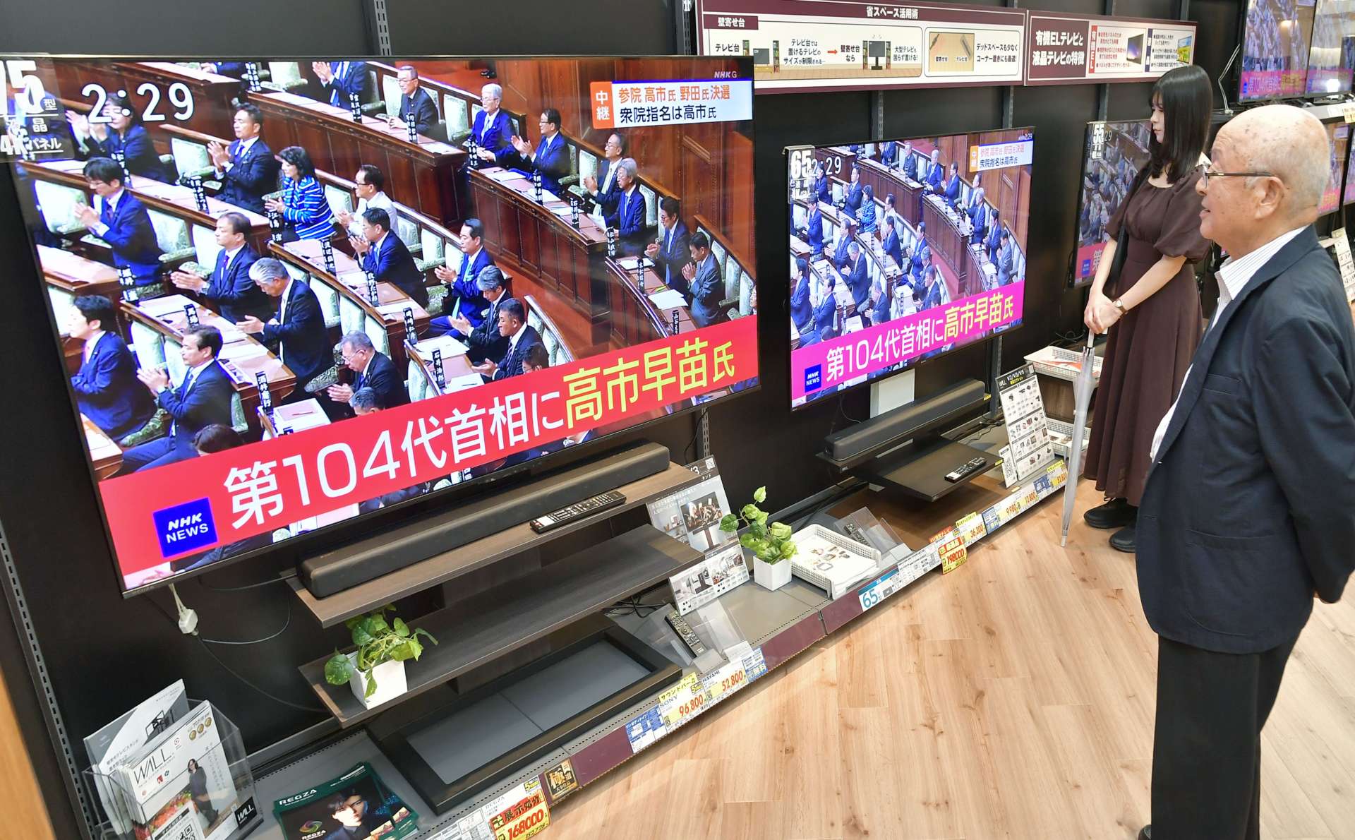 高市早苗氏の首相選出を報じるテレビ画面に見入る買い物客＝２１日午後２時半、鹿児島市金生町のエディオン鹿児島山形屋店