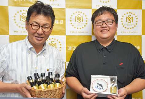 「まぐろ専用醤油」を手にする鹿児島まぐろ船主協会の上夷和輝さん（左）と、市観光特産品協会の鶴徳光さん＝いちき串木野商工会議所