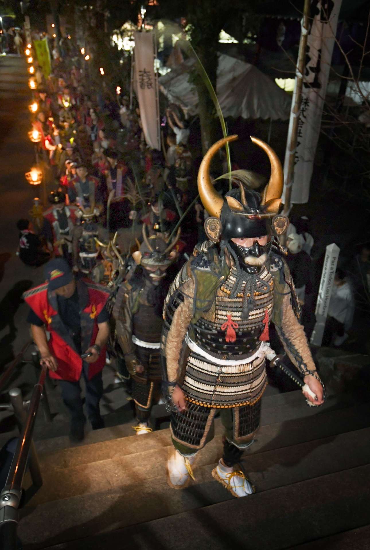 勇壮に参道を進む武者行列＝２５日午後６時２０分、日置市伊集院の徳重神社