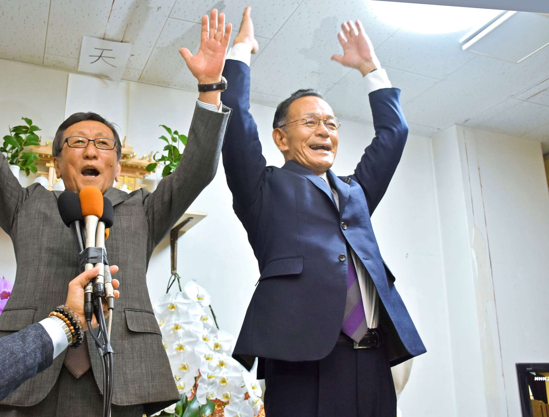 再選が決まり、万歳する中屋謙治さん（右）＝９日、いちき串木野市曙町