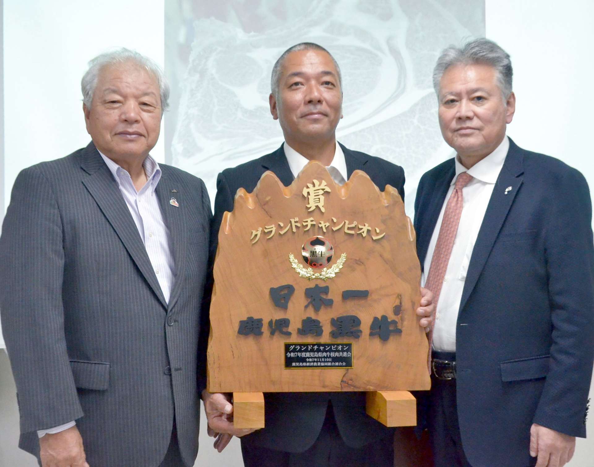 県肉牛枝肉共進会でグランドチャンピオンに選ばれた中村優志さん（中央）＝南九州市のＪＡ食肉かごしま南薩工場