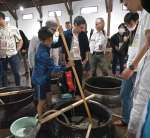 かめに入ったもろみを混ぜる参加者＝南さつま市加世田津貫