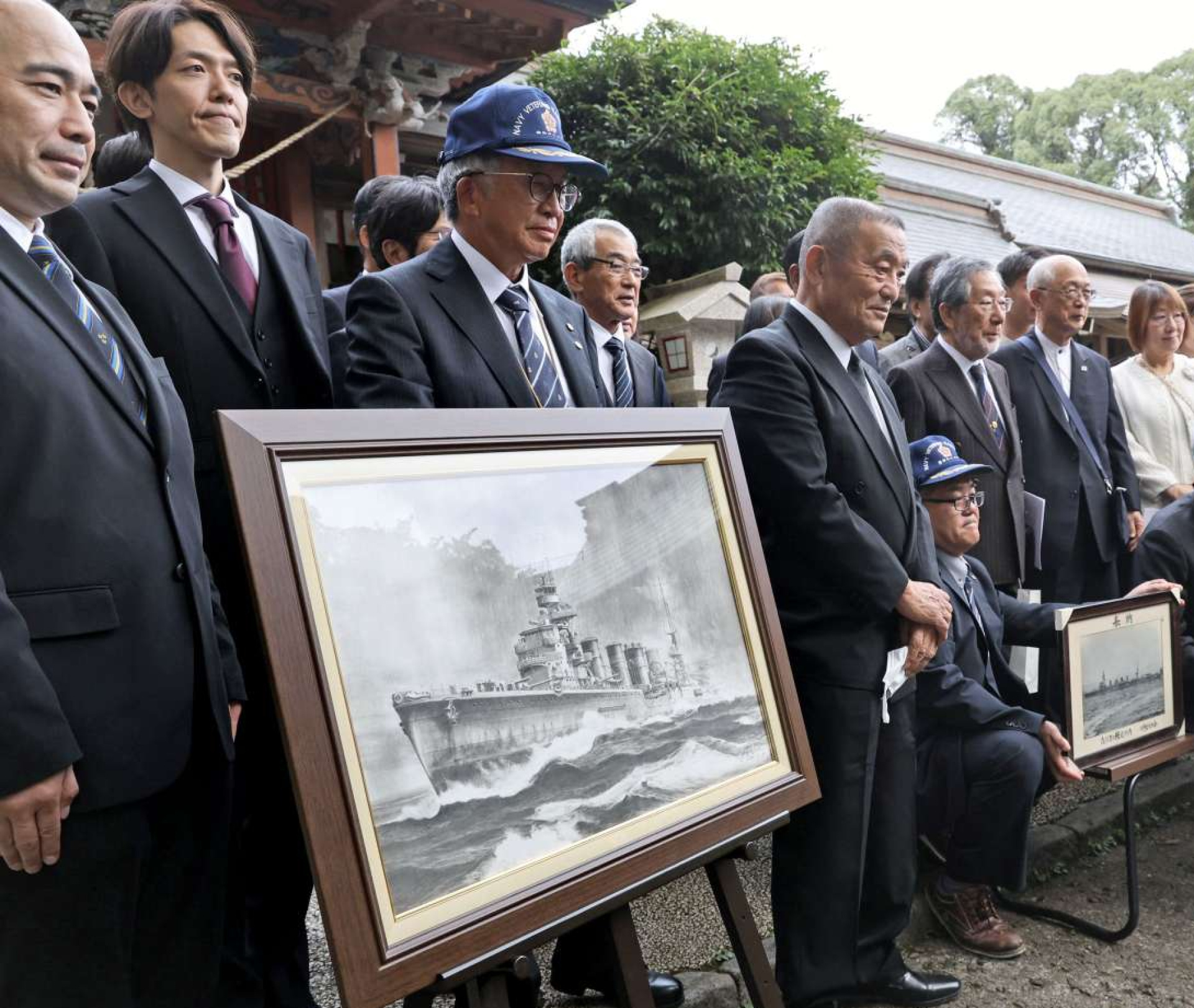 奉納された「川内」の鉛筆画とともに記念撮影する参列者＝薩摩川内市の新田神社