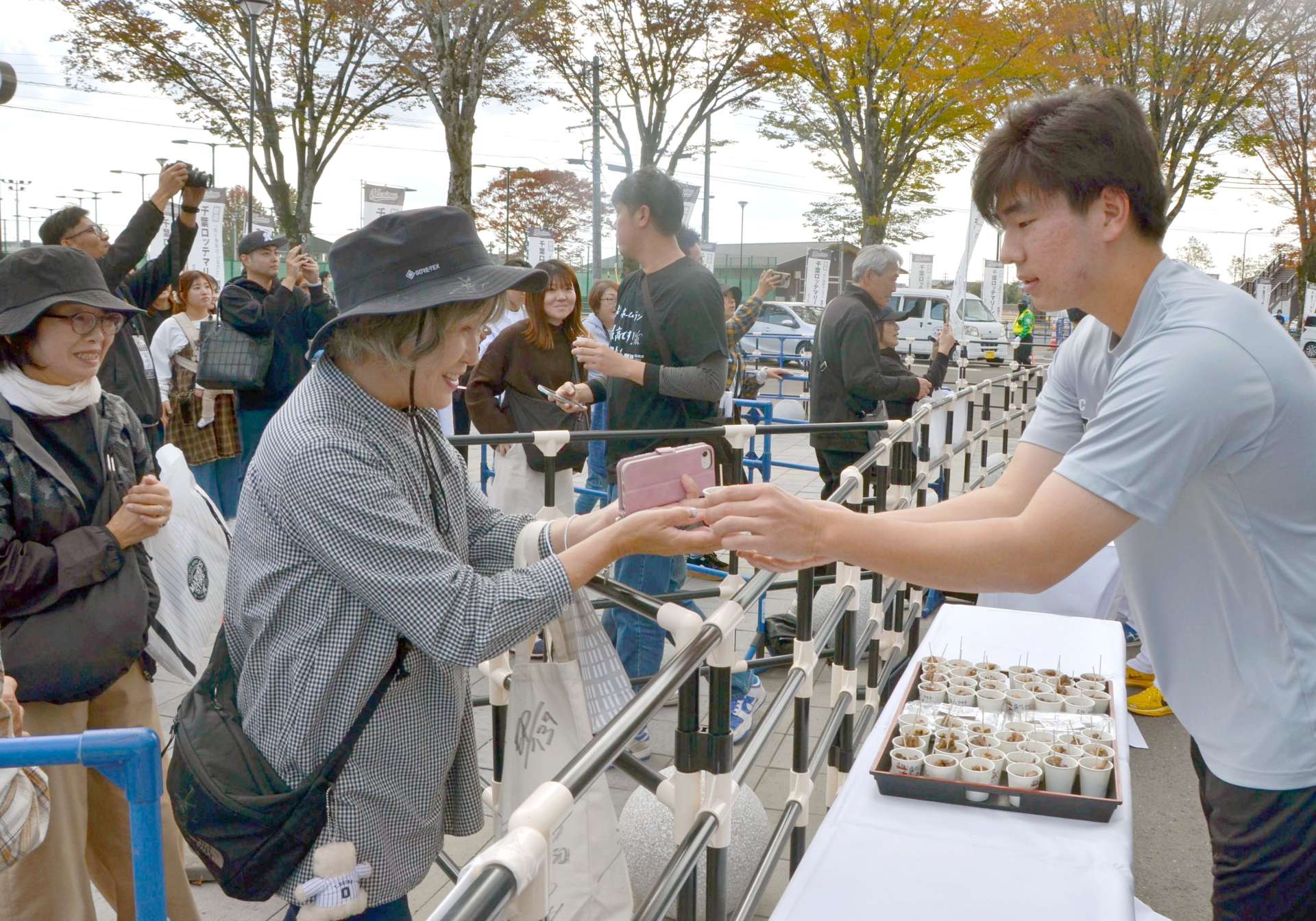 ロッテ選手（右）から炭火焼きを受け取るファン＝都城市妻ケ丘町