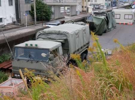 ひっそりと応援を待つ水陸両用車。手前は隊員が待機するトラック＝１２日、鹿児島市錦江町