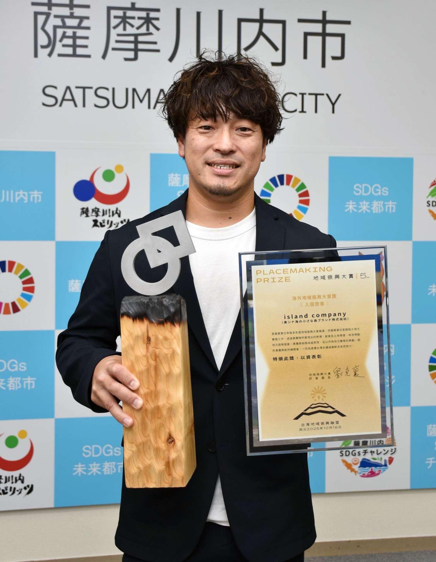 海外地域振興大賞のトロフィーを手にする山下賢太代表＝薩摩川内市役所