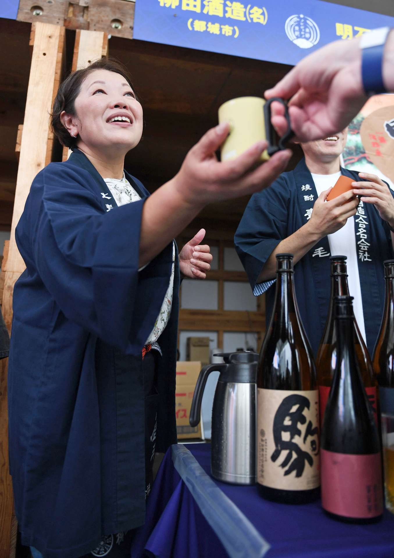 焼酎イベントの来場者に笑顔で接客する都城市職員の原口文代さん＝宮崎市