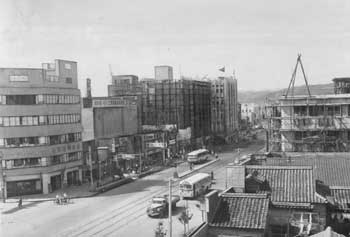 昭和32年、ビル建設でにぎわう鹿児島市の中心街。「東京など大都会とはおもむきがかわり、中小企業の中層ビルが大半」